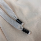 Moncler drawstring ends with small black logo tags on cream shorts