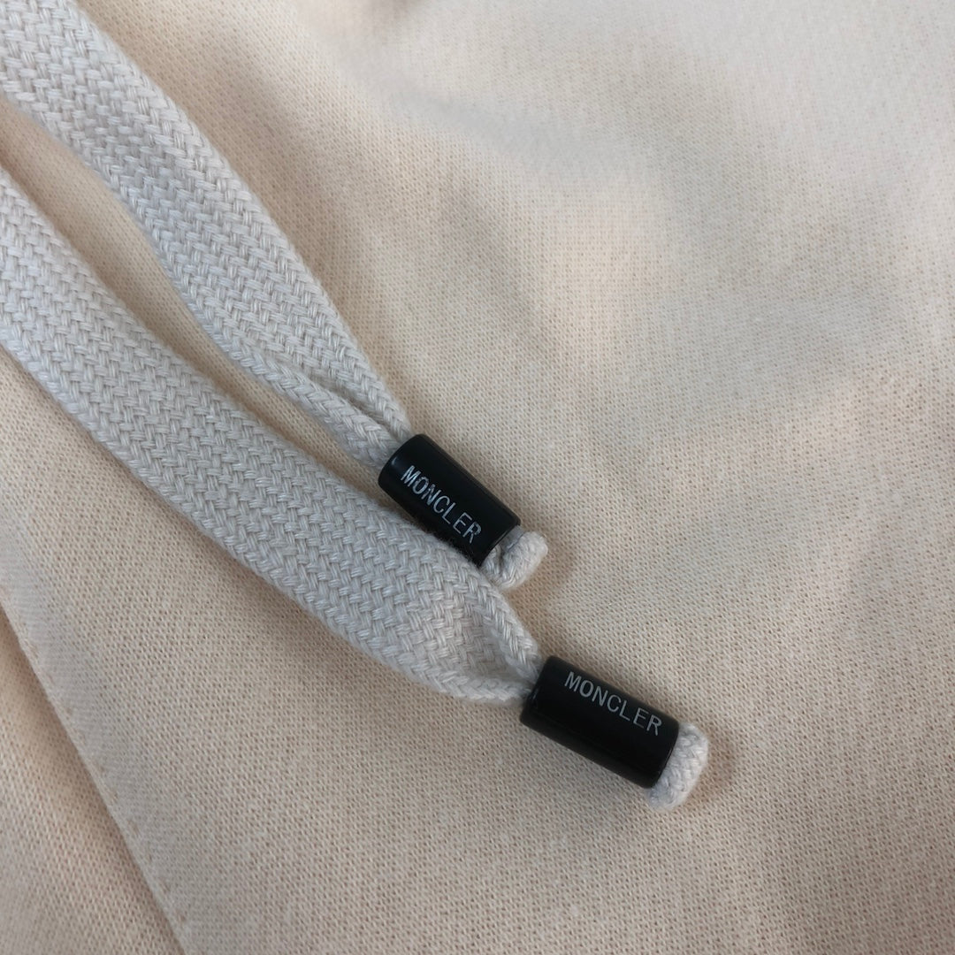 Moncler drawstring ends with small black logo tags on cream shorts