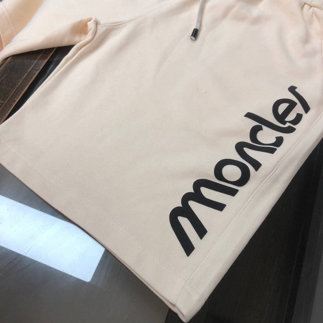 Stone Island cream shorts with large black Moncler logo along the side seam