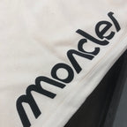 Stone Island cream shorts with close-up black Moncler lettering print