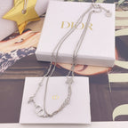 Silver-tone necklace with star and CD charms displayed on white gift boxes