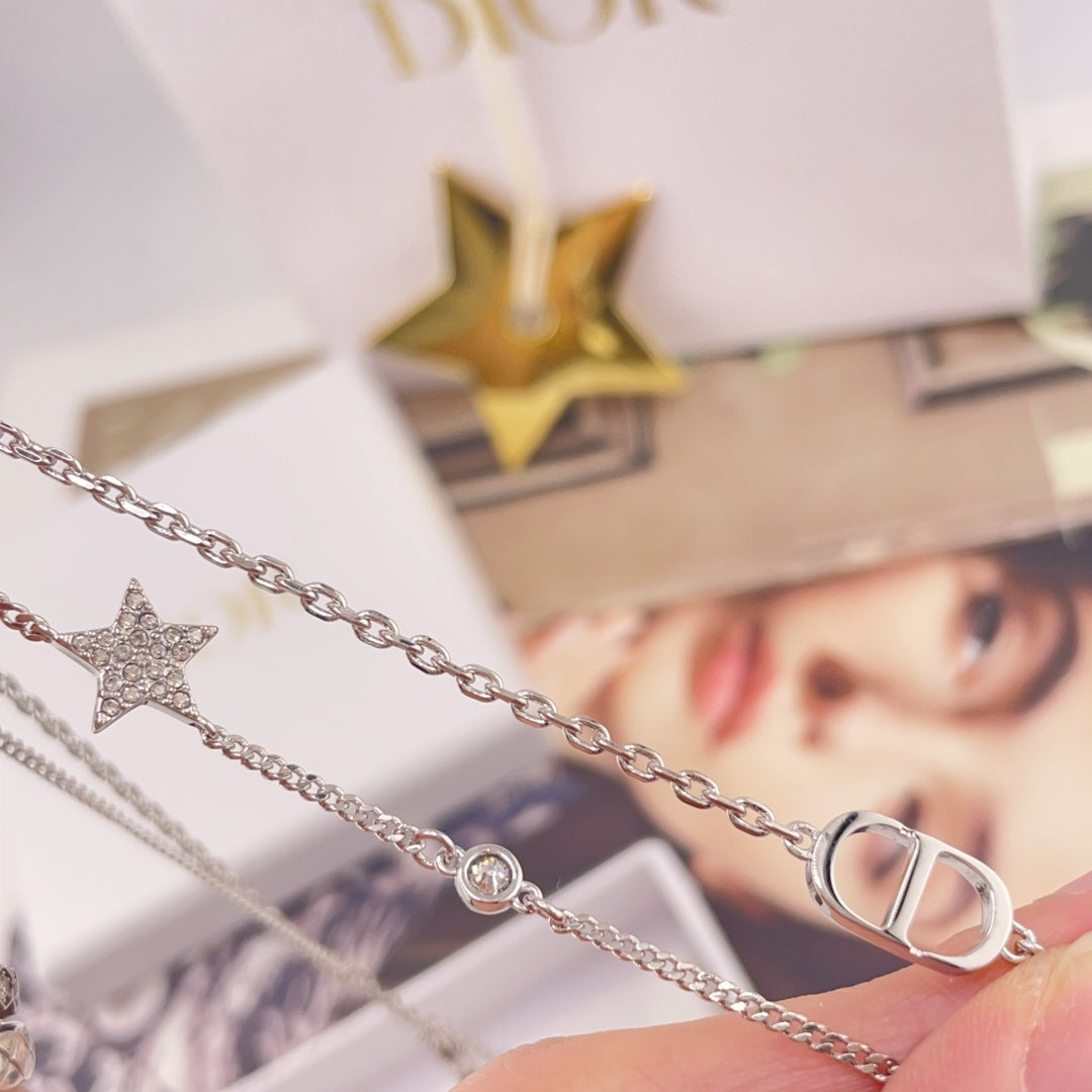 Silver-tone necklace with star charm and CD link pendant, shown on gift box