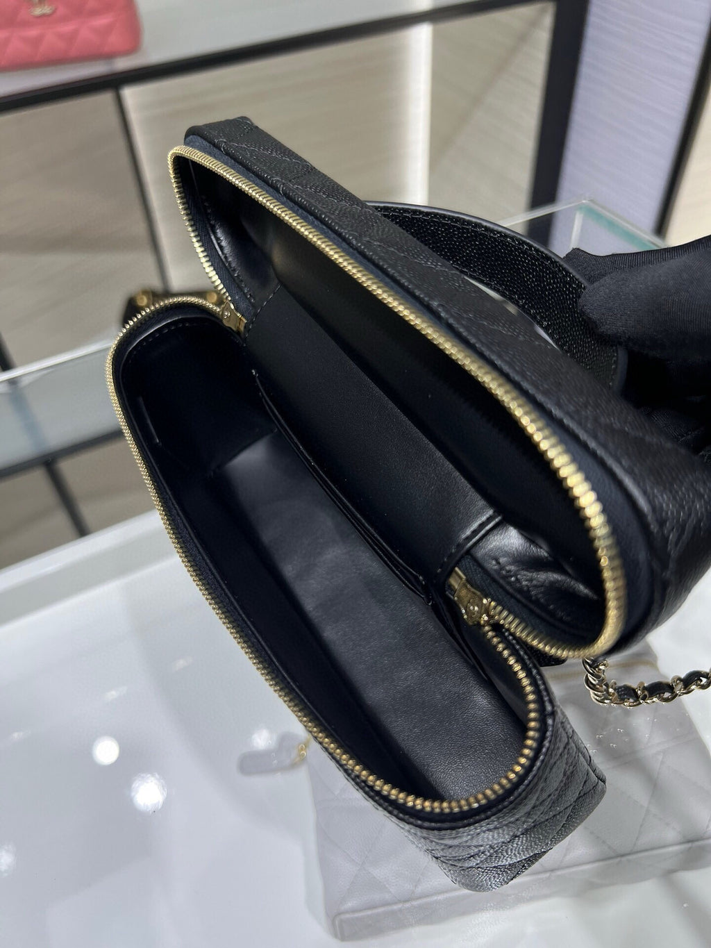 Chanel black leather bag open view with dark lining, zip pocket, and gold zipper