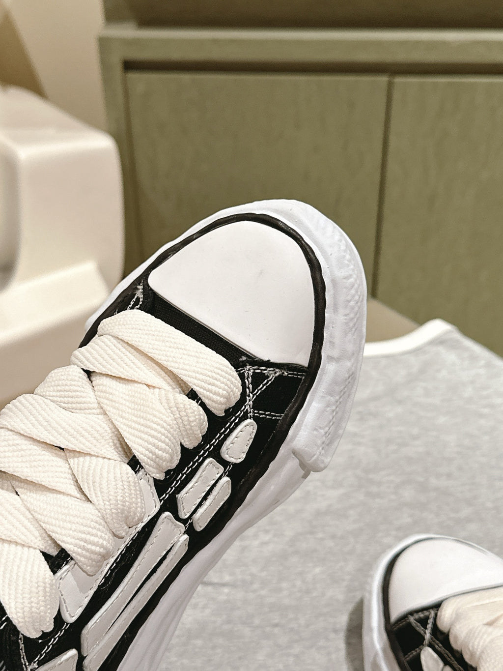 Black and white low-top sneaker, close-up of laces and padded collar.