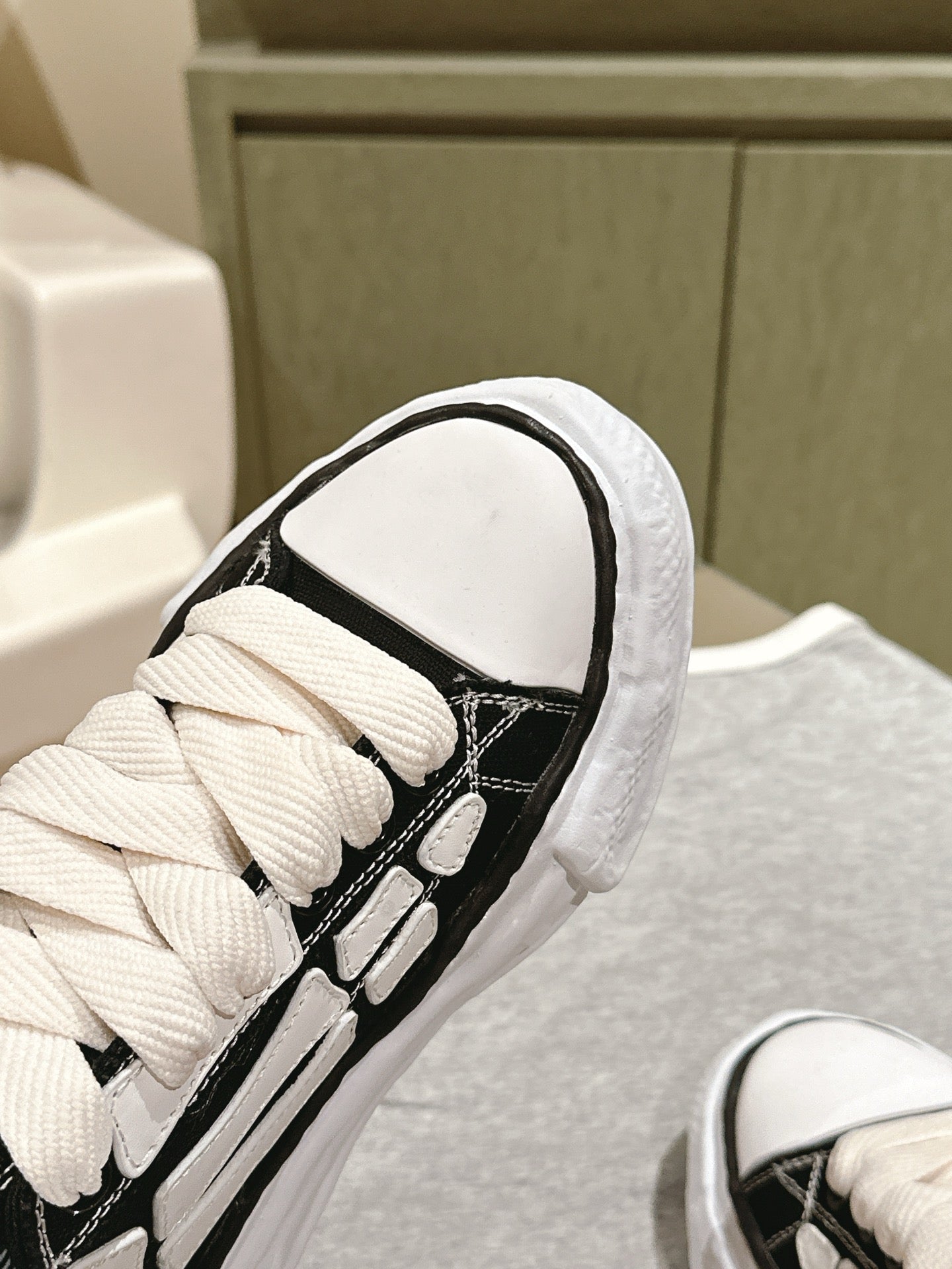 Black and white low-top sneaker, close-up of laces and padded collar.