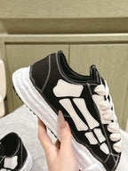 Black and white low-top sneaker, close-up of side panel and lace-up area.