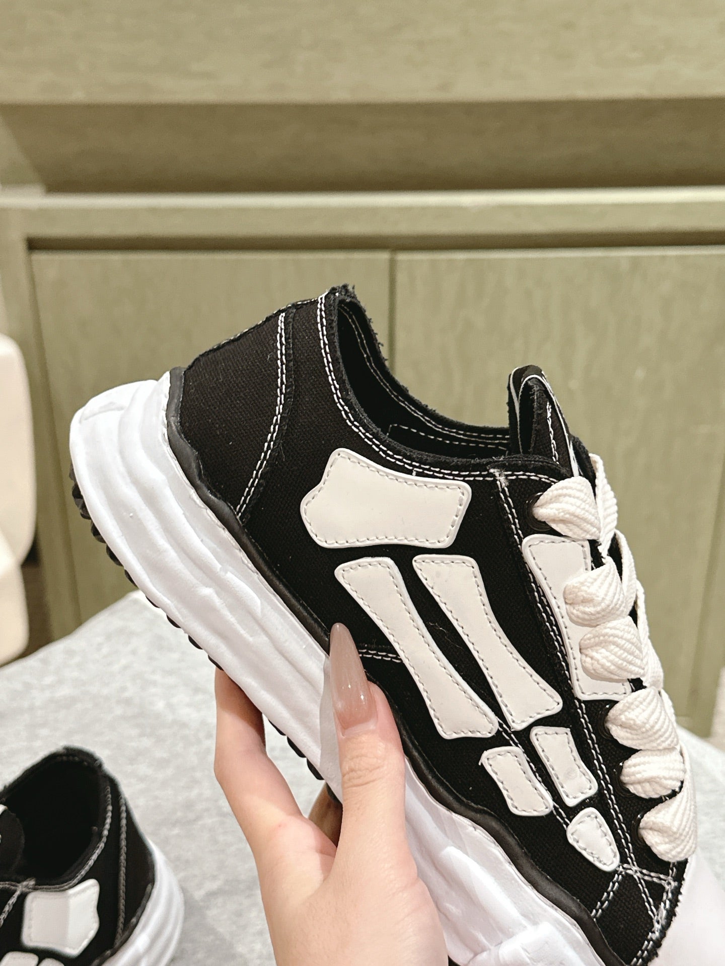 Black and white low-top sneaker, close-up of side panel and lace-up area.