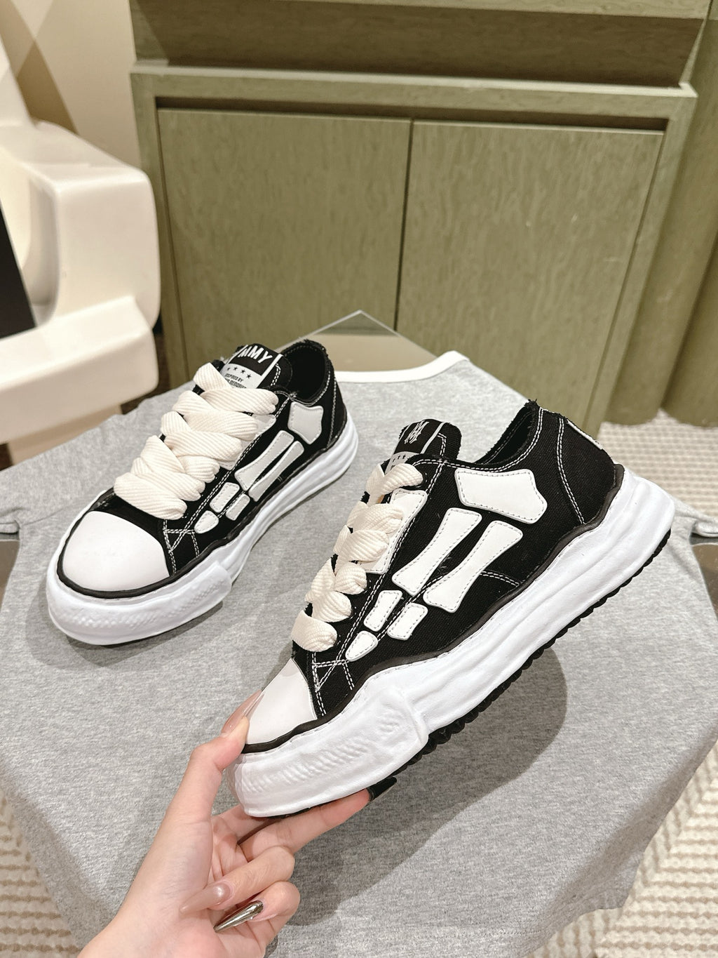 Black and white low-top sneakers, angled view showing lace-up eyelets and logo patch.