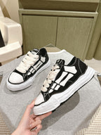 Black and white low-top sneakers, angled view showing lace-up eyelets and logo patch.