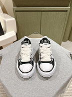 Black and white low-top sneakers with white laces and rubber toe caps.