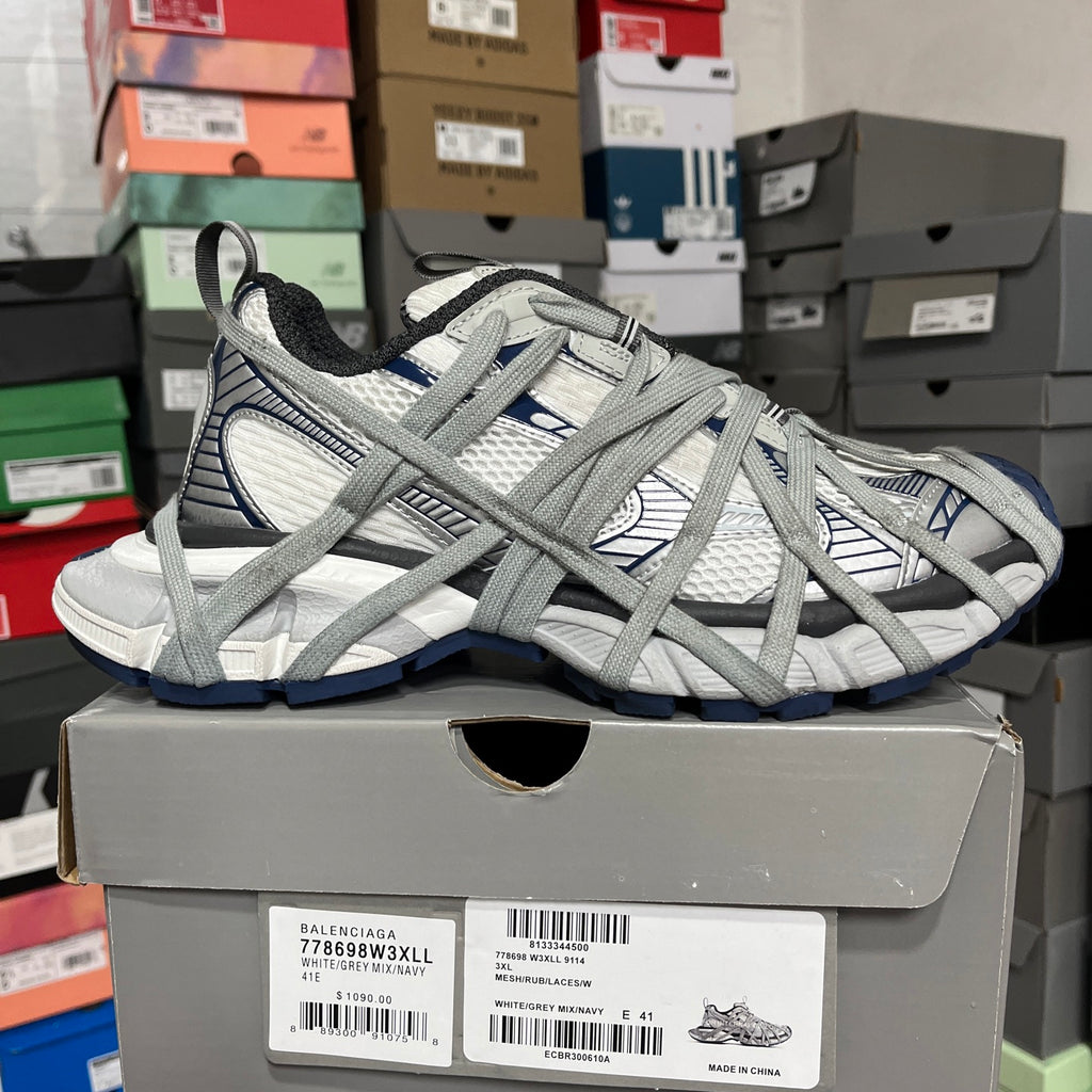 Grey and white lace-up athletic shoes with blue trim on a padded, chunky sole.