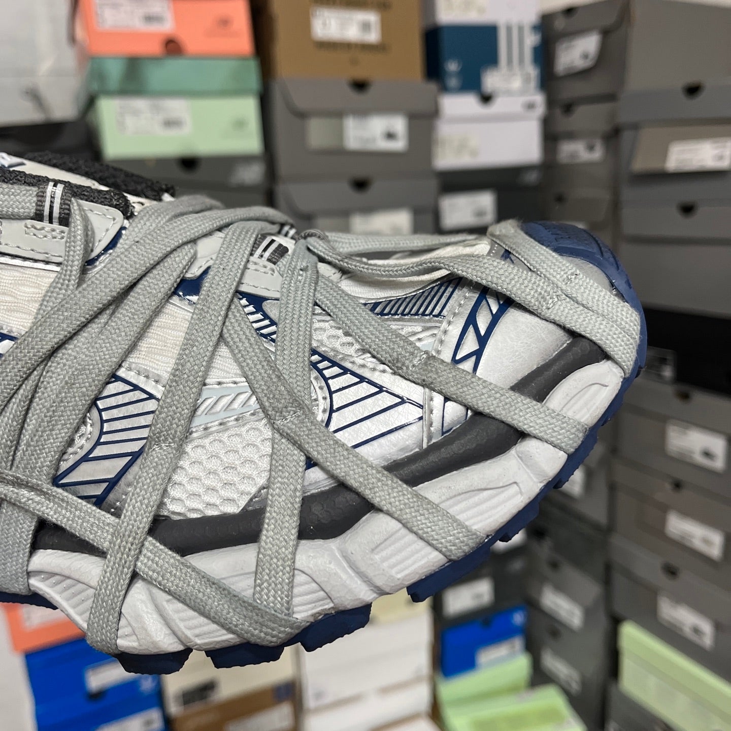 Close-up of grey lace-up athletic shoe with blue-lined straps and textured upper.