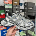 Grey and white athletic shoes with blue accents, lace-up design and cushioned sole.