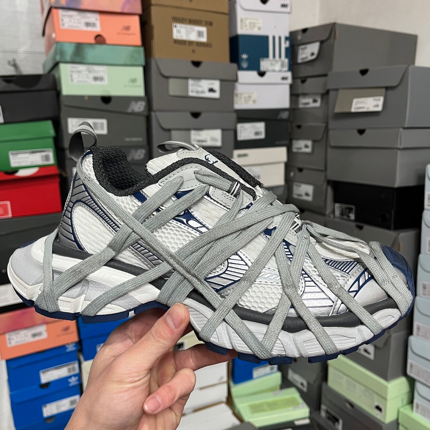 Grey and white athletic shoes with blue accents, lace-up design and cushioned sole.
