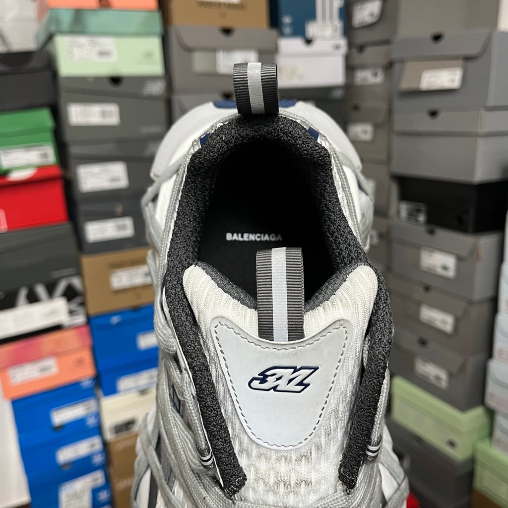 Back view of grey athletic shoe with fabric heel tab and white logo patch.