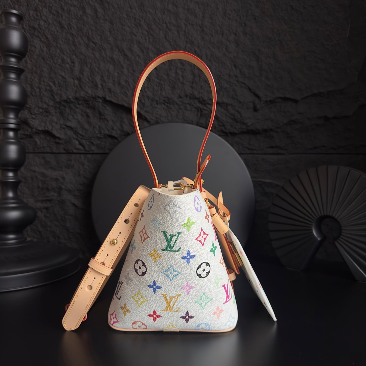 Louis Vuitton monogram bucket bag with tan straps, orange piping, and colorful logo print