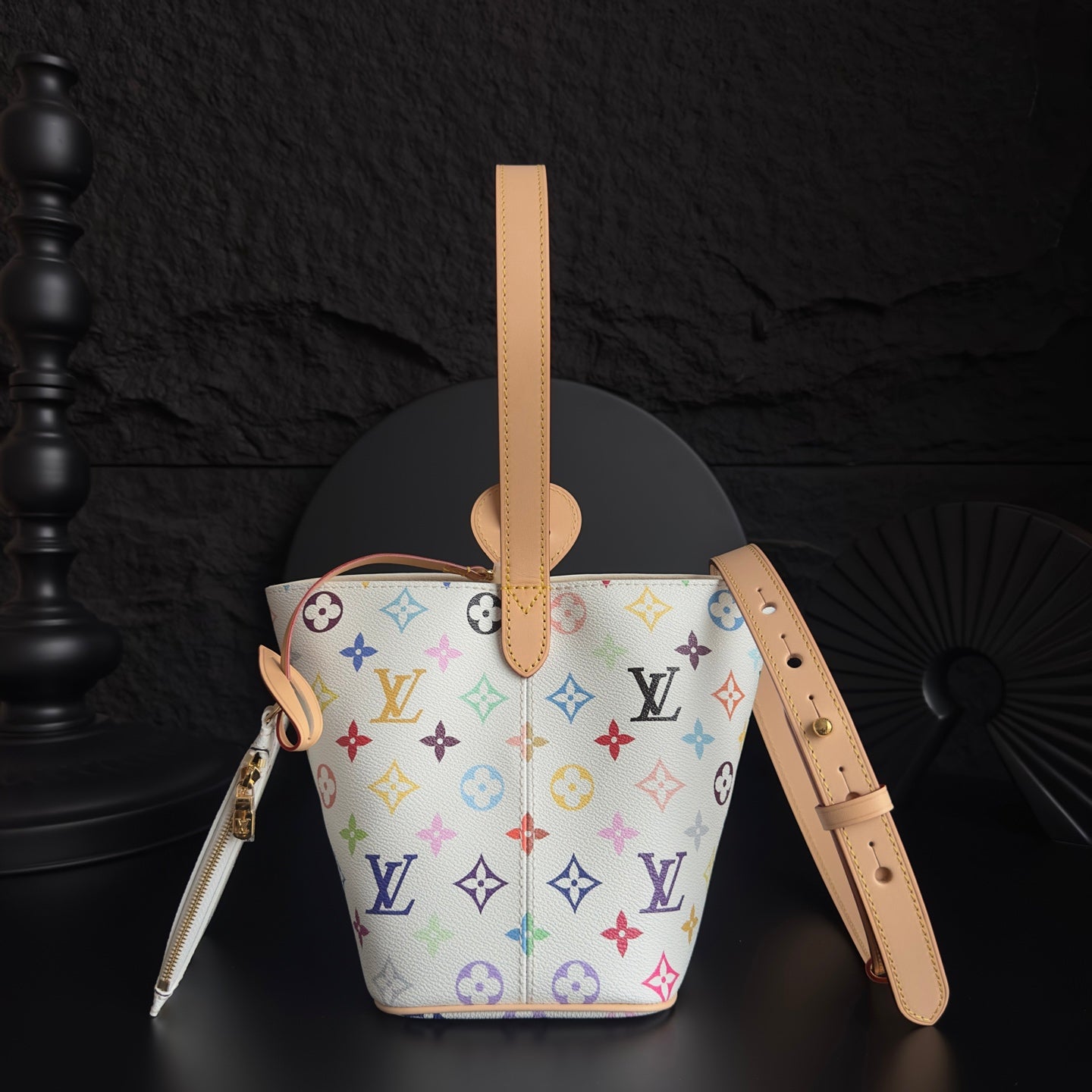 Louis Vuitton monogram bucket bag with tan handles, zipper pocket, and colorful logo print