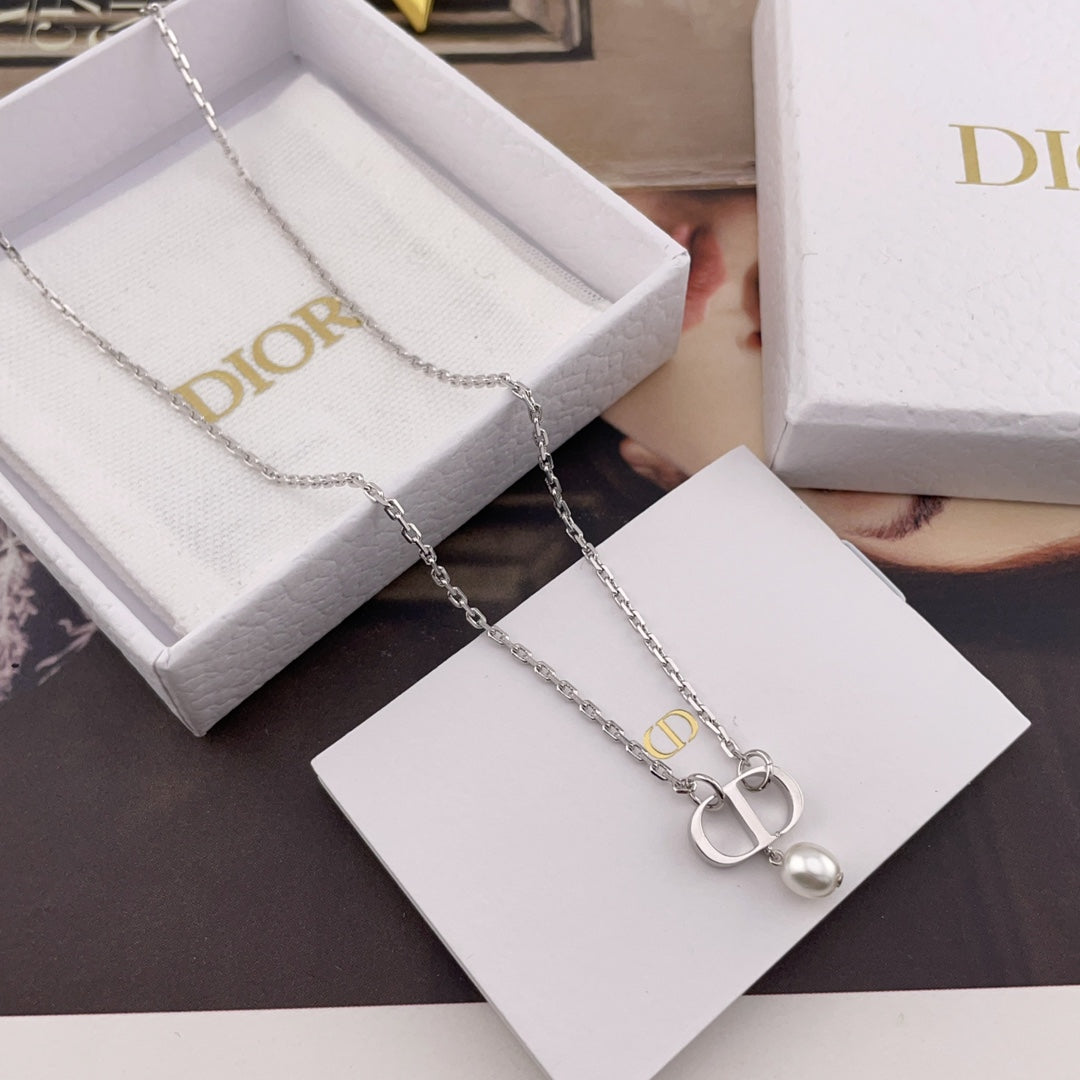Dior necklace with silver chain and pendant charm laid on a white card