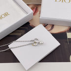 Dior necklace with silver charm and pearl detail on a white DIOR card