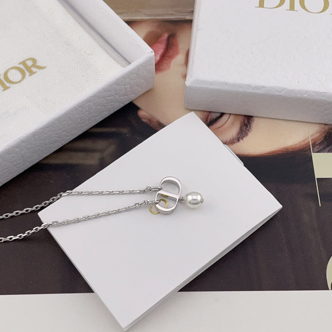 Dior necklace with silver charm and pearl detail on a white DIOR card