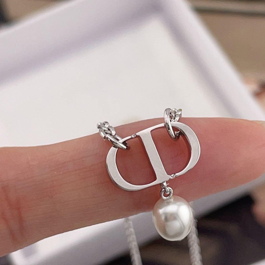 Dior necklace charm with silver links and pearl bead held in hand