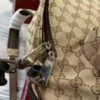 Gucci men's mini backpack close-up of metal zipper pull and beige GG-pattern strap