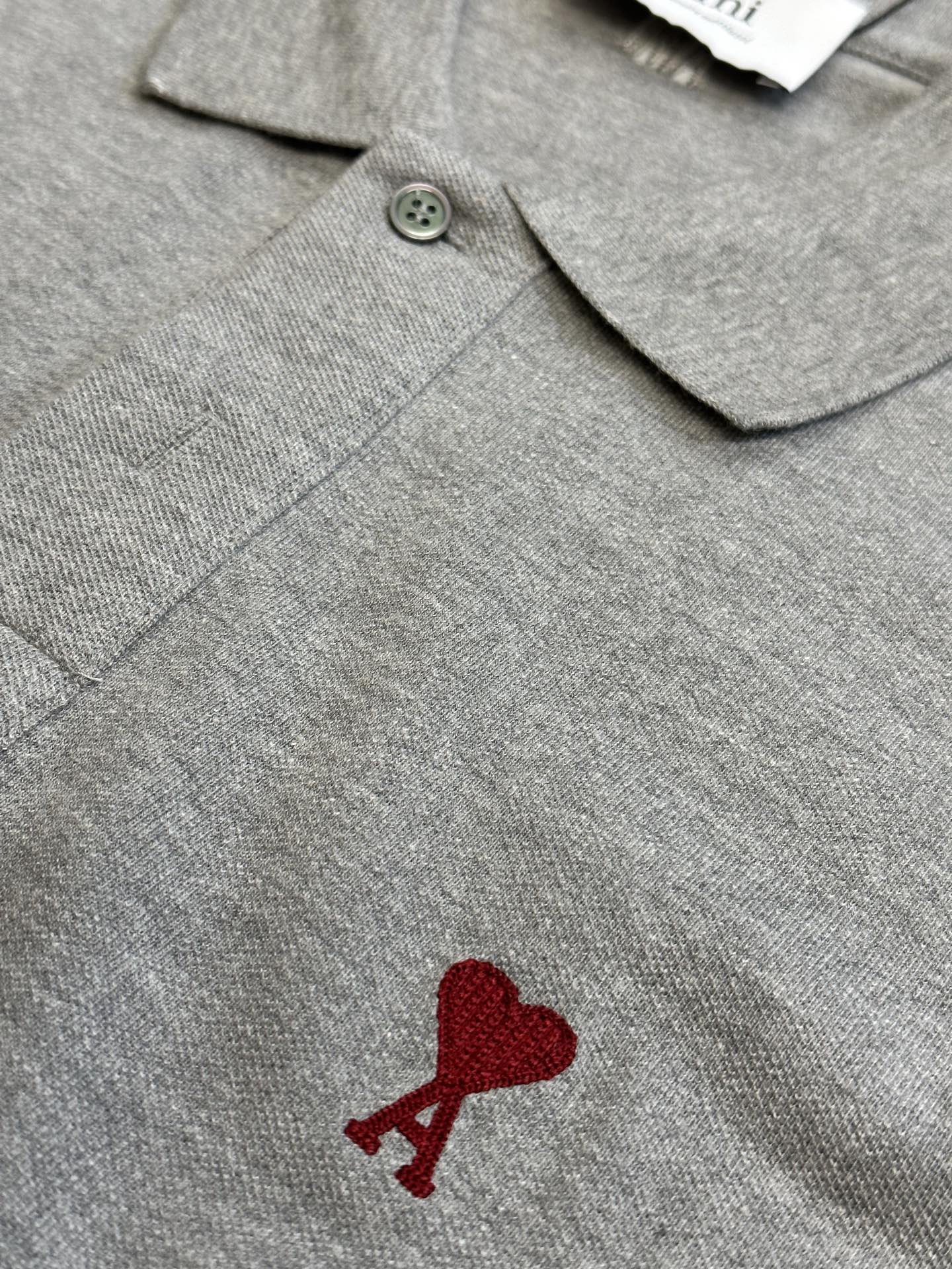 Gray polo shirt button placket with embroidered red heart A logo