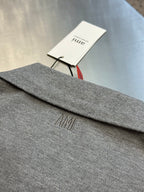 Light gray polo shirt hem with embroidered AMI logo