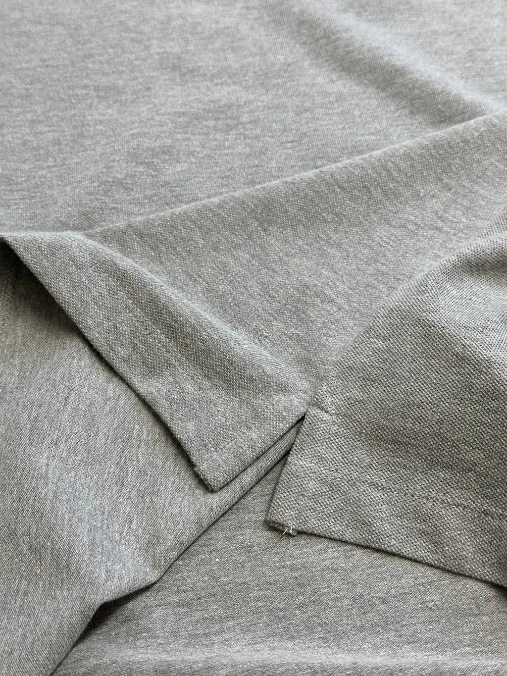 Light gray polo shirt fabric and seam detail with short sleeve edge