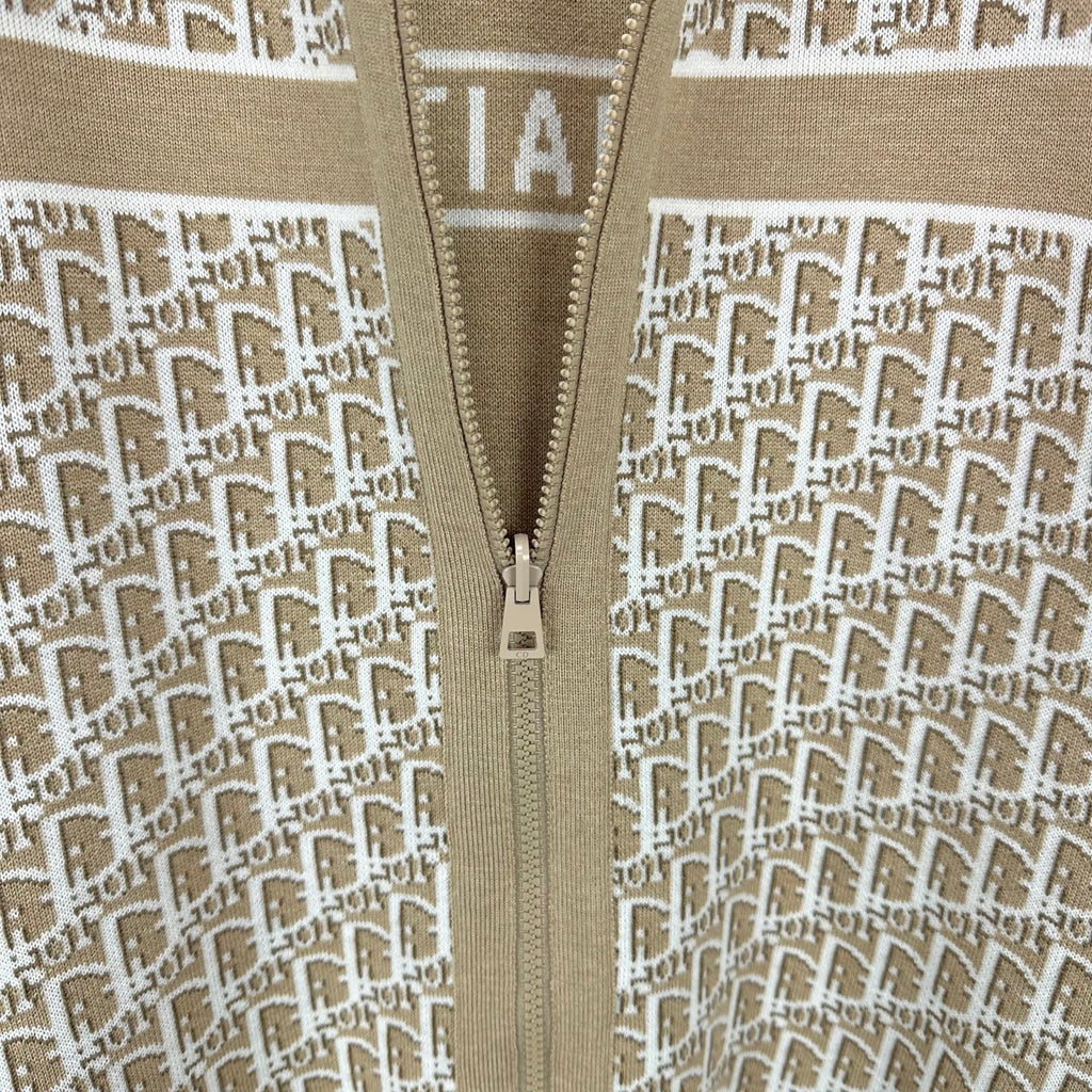 Beige knit jacket close-up of center zipper and white monogram pattern