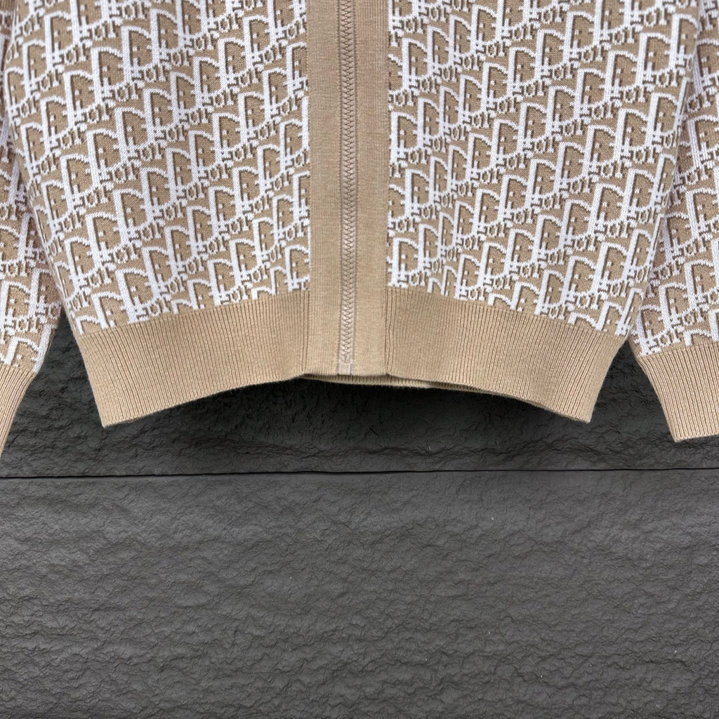 Beige knit zip jacket hem close-up with white monogram panels and ribbed cuff
