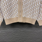 Beige knit zip jacket hem close-up with white monogram panels and ribbed cuff