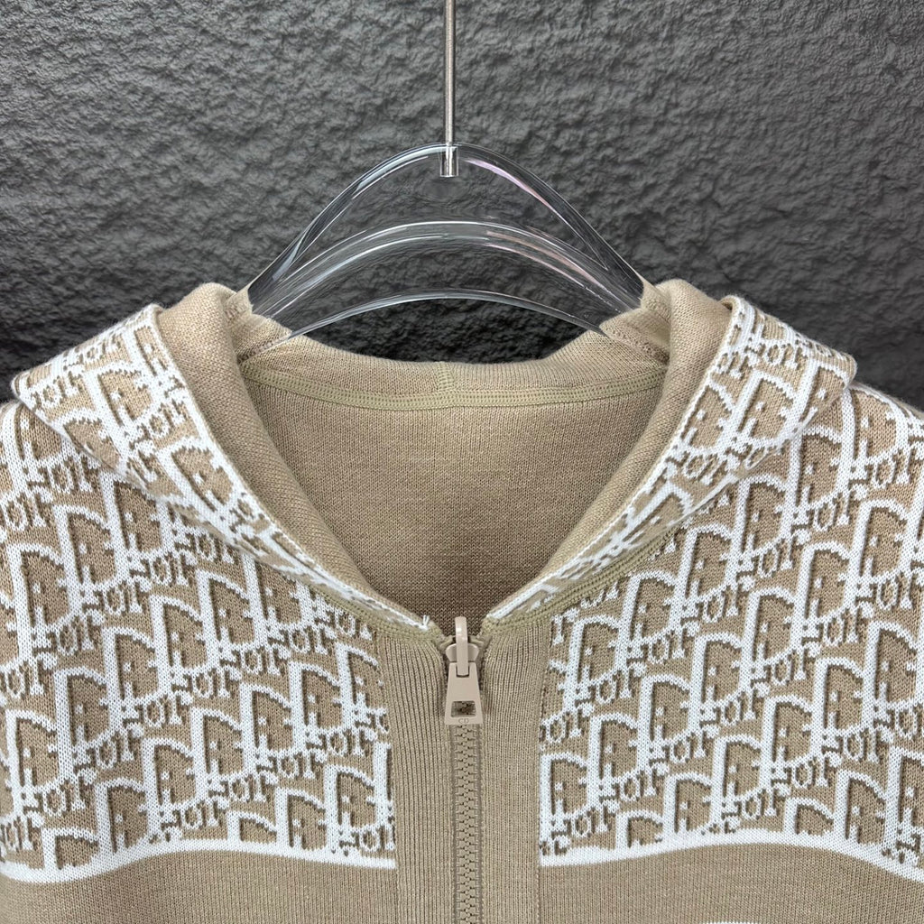 Beige hooded zip jacket close-up with white monogram knit and zipper pull