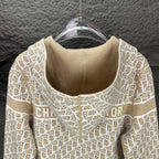 Beige knit hooded zip jacket close-up with white monogram pattern at neckline