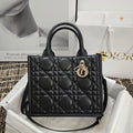 Black quilted handbag with top handles and gold logo charm hardware