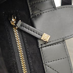 Black handbag zipper detail with gold-tone pull and stitched edge