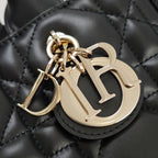 Gold-tone logo charm and keyring hardware on black quilted handbag