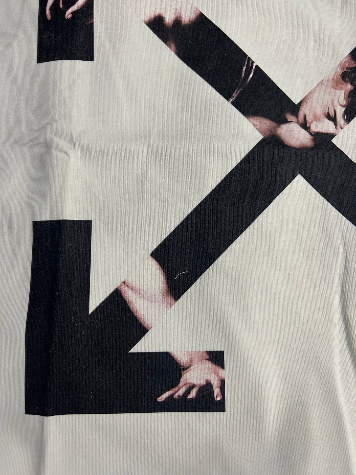 Off-white T-shirt close-up with arrow X graphic and black block accents