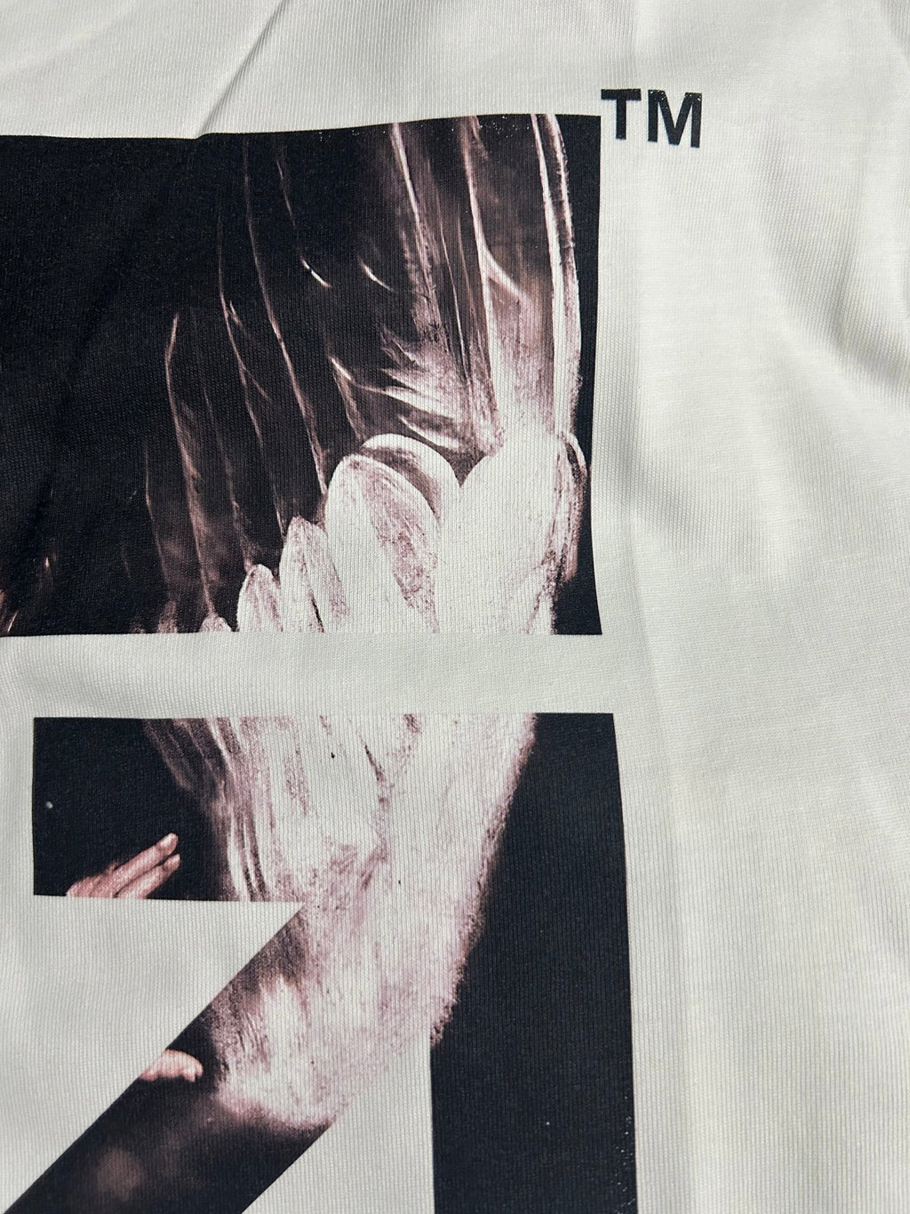 Off-white T-shirt close-up showing black-and-white graphic panel and arrow X