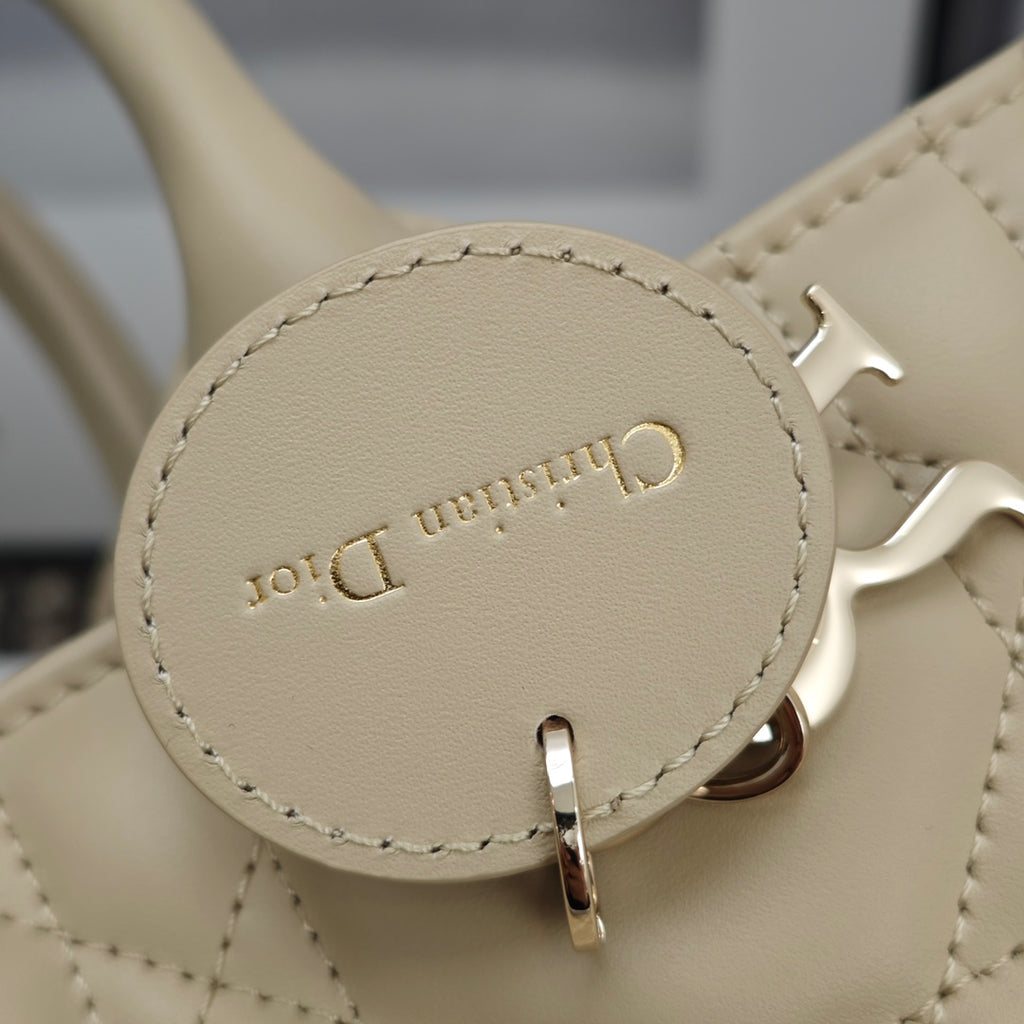 Beige quilted handbag rear logo patch with metal hook hardware