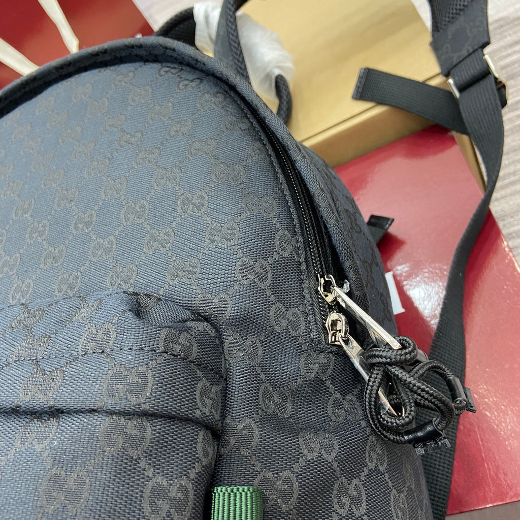 Gucci men's monogram backpack top corner with braided drawstring cord and metal clasp
