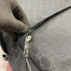 Monogram backpack corner with metal zipper pull and stitched fabric edge