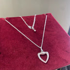 Layered silver heart pendant necklaces on dark red fabric display