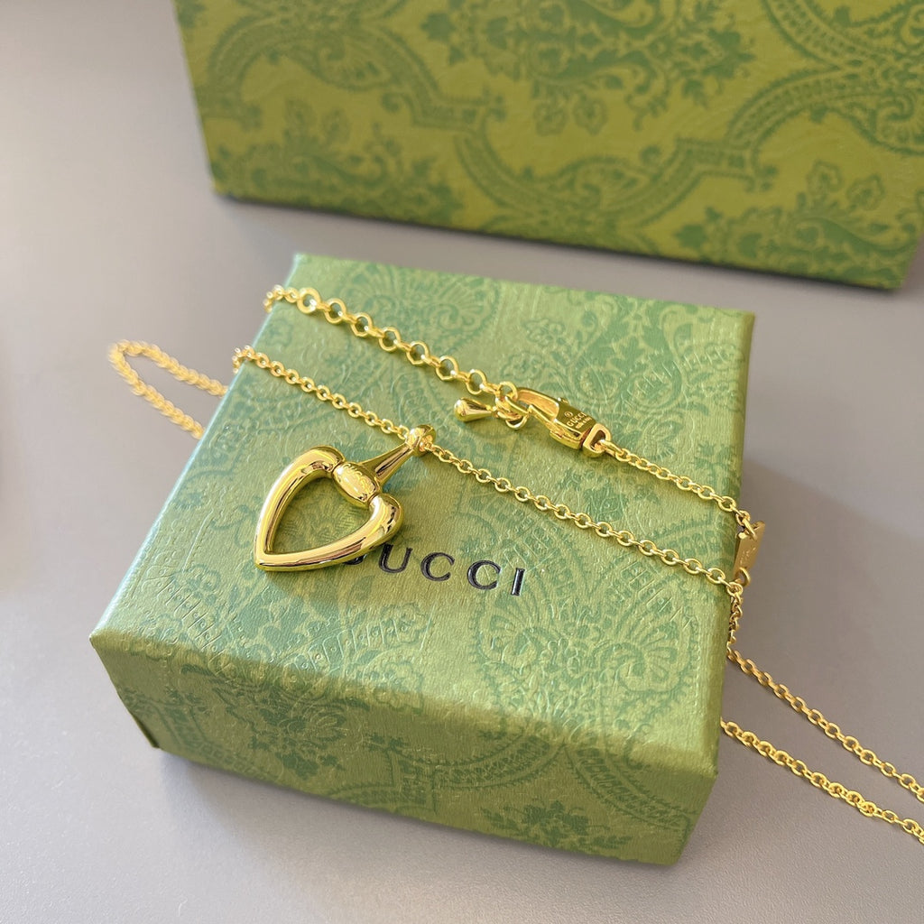 Gold-tone heart pendant necklace with chain and heart charm resting on a box