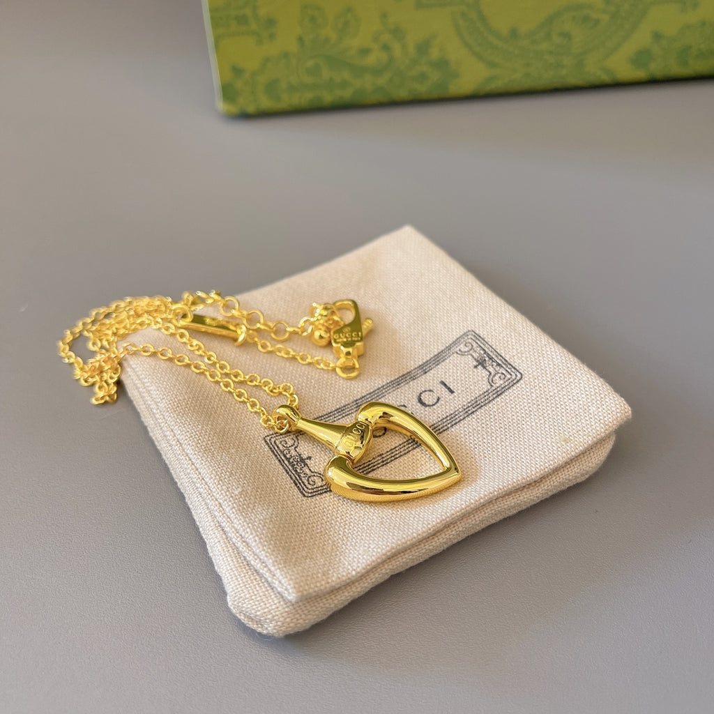 Gold-tone heart pendant necklace with clasp, placed on fabric pouch