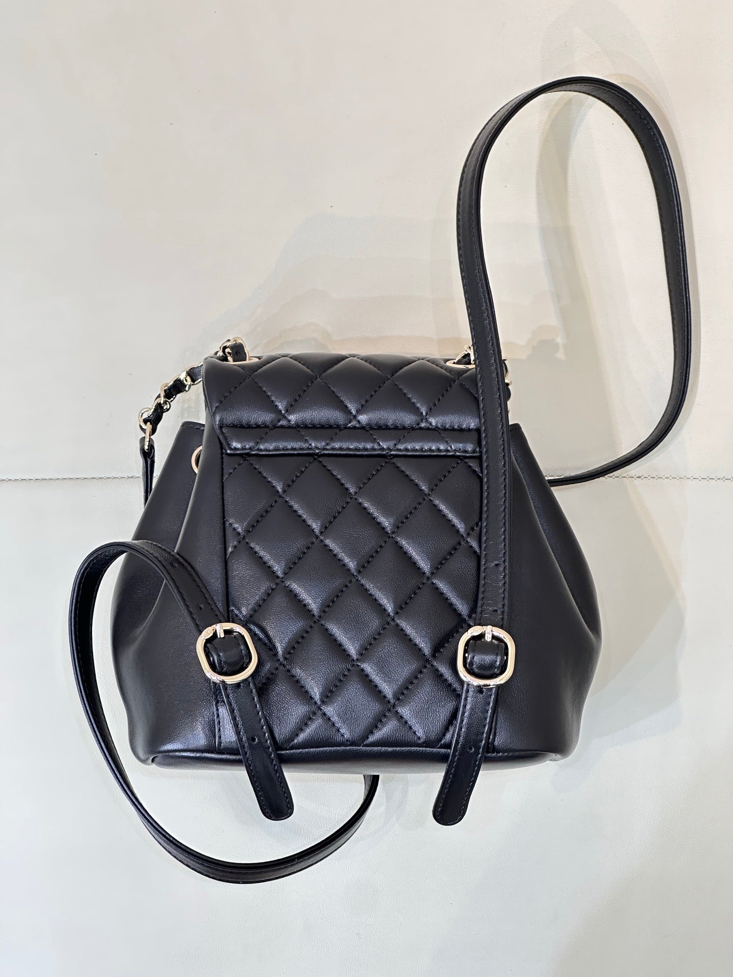 Dark navy quilted leather mini bag with front buckle straps and chain loop