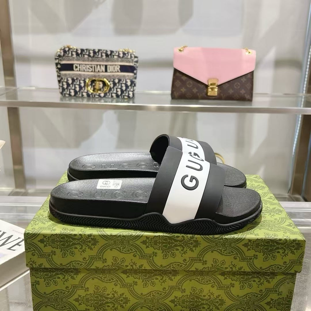 Black slide sandals with white Gucci logo strap on textured footbed