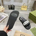Black slide sandal sole with embossed pattern and white Gucci logo strap on top