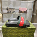 Black Gucci slide sandals on green box, green and red logo strap