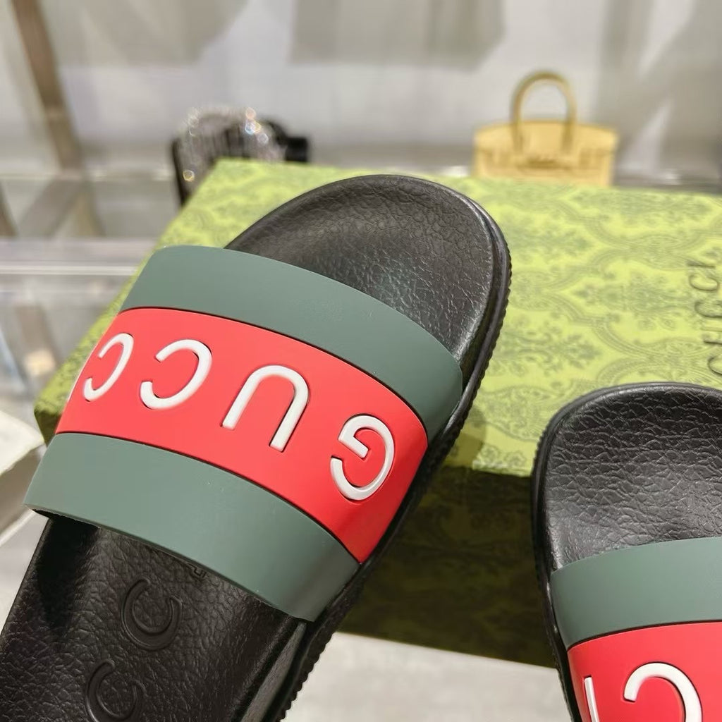 Close-up of black Gucci slide sandal strap with green base and red Gucci band